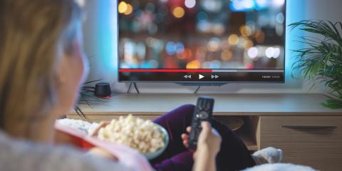 Eine Frau sitzt mit Popcorn vor dem Fernseher und streamt ein Video (Bildquelle:  Kaspars Grinvalds - stock.adobe.com)